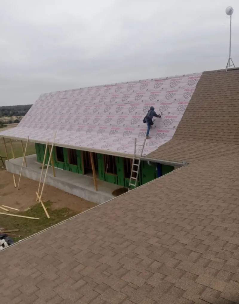 Worker preparing underlayment for a metal roof installation in Hampstead